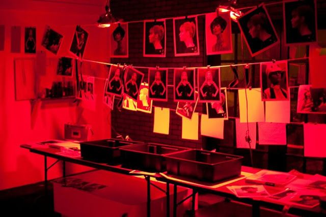 a room with red lights and pictures on the wall, all hanging up in rows