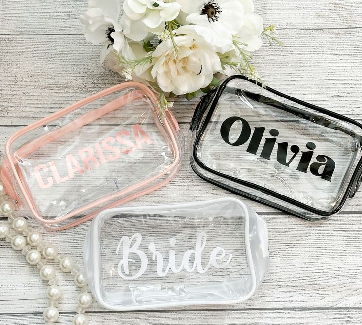 three clear bags with bride and groom's names on them sitting next to flowers