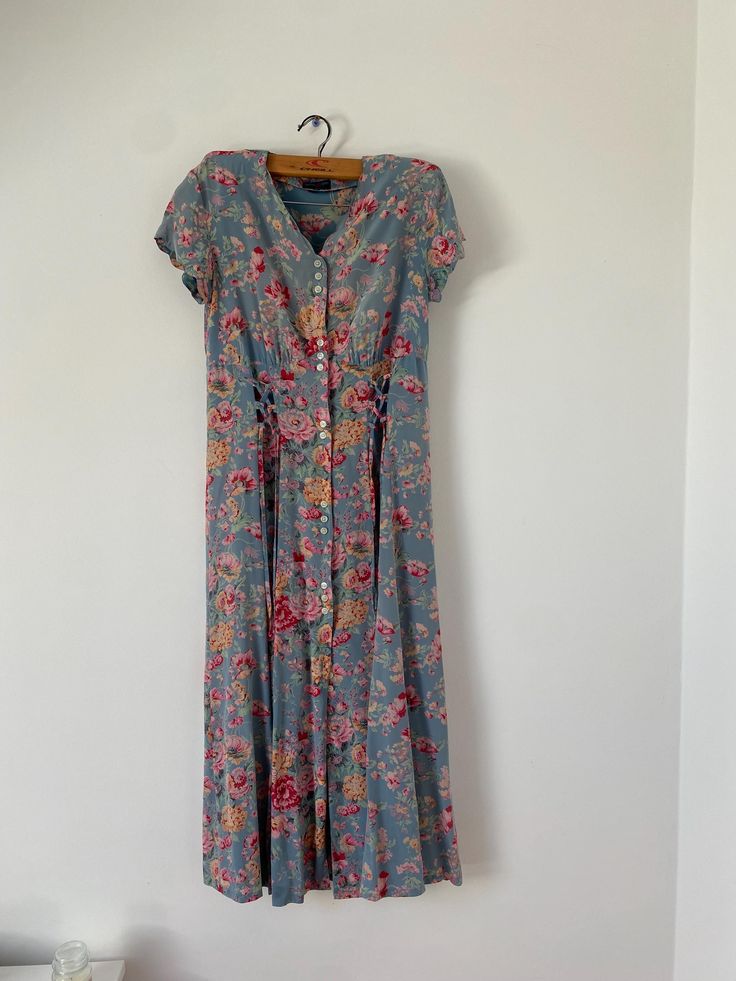 Vintage 100% silk dress.  The dress features a beautiful blue base adorned with vibrant floral and rose patterns, exuding classic charm. Designed to be lightweight and airy, this full-length dress is perfect for summer. The front button closure adds a touch of sophistication to this high-quality silk piece. Elevate your wardrobe with this exquisite vintage find. Size: Small. Measurements: Length: Chest: Waist: Hip: Skirt opening: Beautiful vintage condition, some signs of wear. 10/9.  Model is 1 Floral Print Short Sleeve Rayon Dress, Short Sleeve Floral Print Rayon Dresses, Casual Silk Maxi Dress With Floral Print, Floral Print Rayon Dress With Short Sleeves, Blue Ditsy Floral Print Maxi Dress For Garden Party, Bohemian Fitted Floral Dress For Daywear, Fitted Bohemian Floral Dress For Daywear, Casual Silk Dress With Floral Print, Blue Bohemian Floral Dress With Ditsy Print