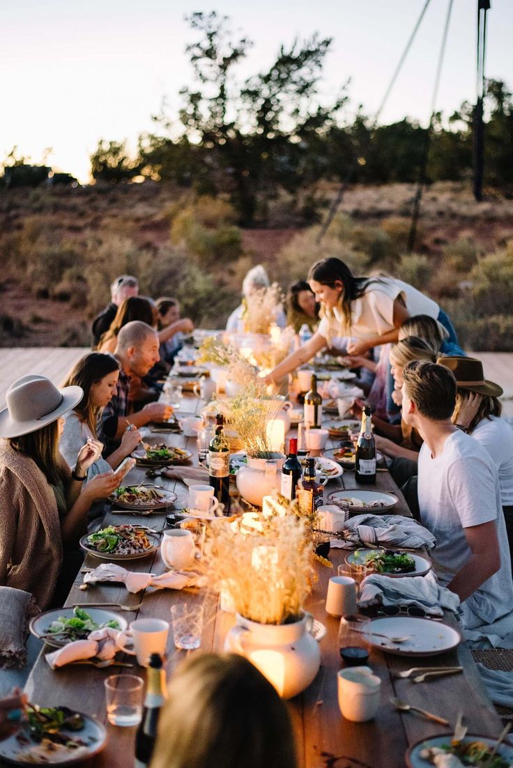 a group of people sitting at a long table with food and drinks in front of them