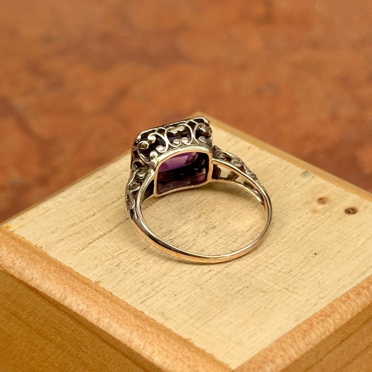 Estate 14KT yellow gold bezel-set, emerald-cut, purple amethyst ring with filigree design on half of the band and hidden under the bezel setting. Size 5.25 Can be resized contact us for pricing Weight: 2.40 grams 9mm x 7mm center, emerald cut amethyst stone bezel-set in yellow gold Some scratches to the stone Stamped 14K, but hard to read Fine Jewelry Amethyst With Bezel Setting, Classic Octagon Amethyst Ring As Gift, Classic Octagon Amethyst Ring As A Gift, Classic Octagon Amethyst Ring For Gift, Classic Emerald Cut Purple Rings, Classic Purple Emerald Cut Rings, Heirloom Jewelry With Octagon Bezel Setting, Victorian Purple Ring With Center Stone, Victorian Style Purple Ring With Center Stone