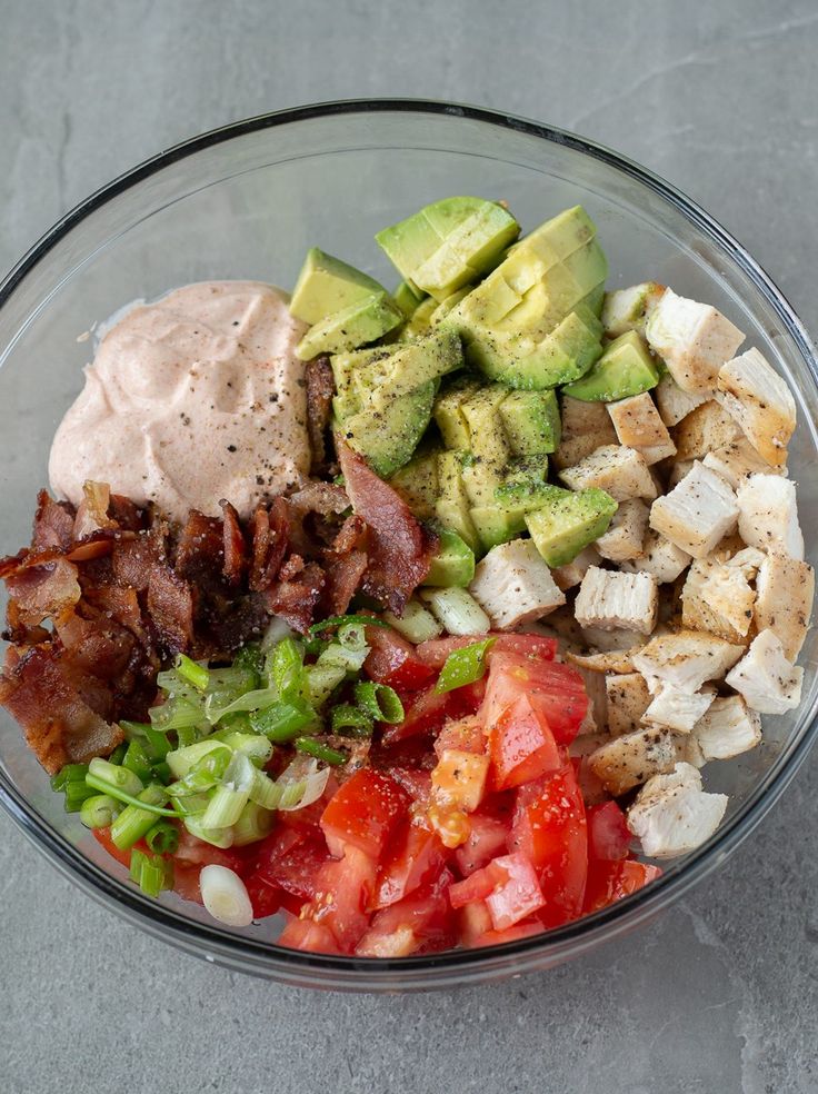 a glass bowl filled with different types of vegetables and meats on top of each other