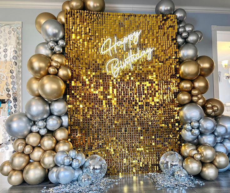 a gold and silver birthday backdrop with balloons