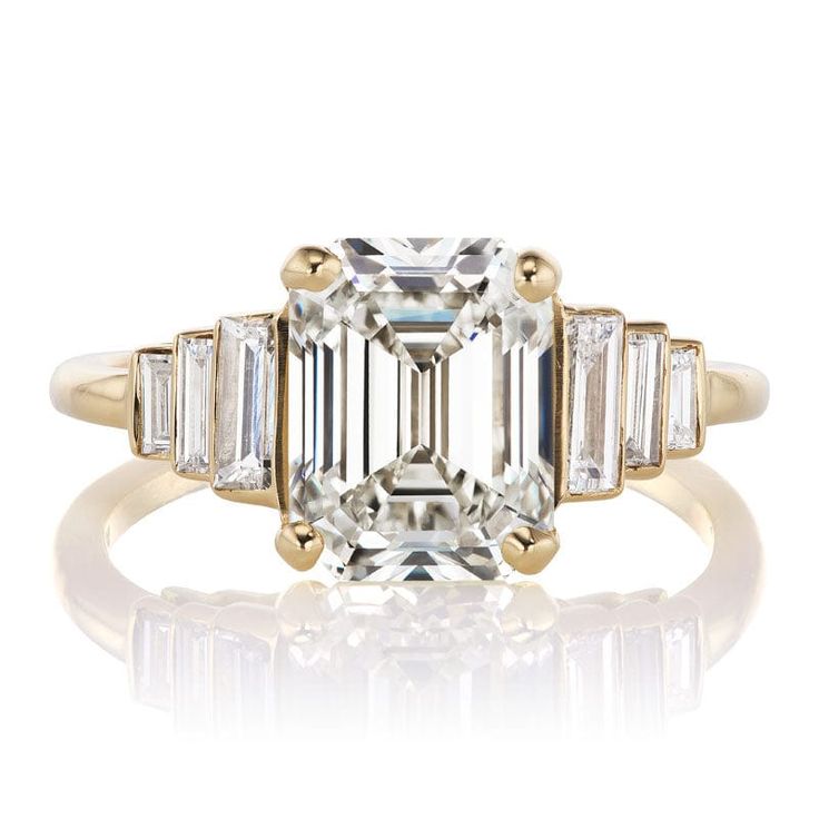 an emerald cut diamond ring with three baguets in yellow gold and white diamonds