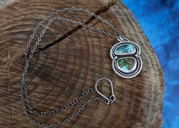 This necklace features a gorgeous pair of Stormy Mt. Turquoise full of blues and a rocky matrix. It’s wrapped in two layers of twist wire and adorned with starburst accents. The silver is oxidized to bring out all the fine details and depth and is topped off with a brushed finish. The pendant hangs on a 16’’-18’’ adjustable sterling silver chain with a handmade clasp. The chain has been darkened to match the patina on the pendant. Handmade out of sterling silver and natural stones, including Sto Adjustable Hand-strung Turquoise Sterling Silver Necklace, Hand-strung Silver Turquoise Necklace, Artisan Hand-strung Turquoise Necklace Gift, Unique Silver Hand-strung Turquoise Necklace, Artisan Silver-toned Turquoise Cabochon Necklace, Twisted Wire, Chain Lengths, Matrix, Sterling Silver Chains