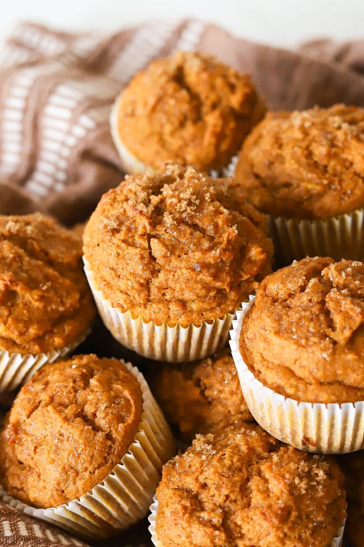 a pile of muffins sitting on top of a brown cloth covered tablecloth