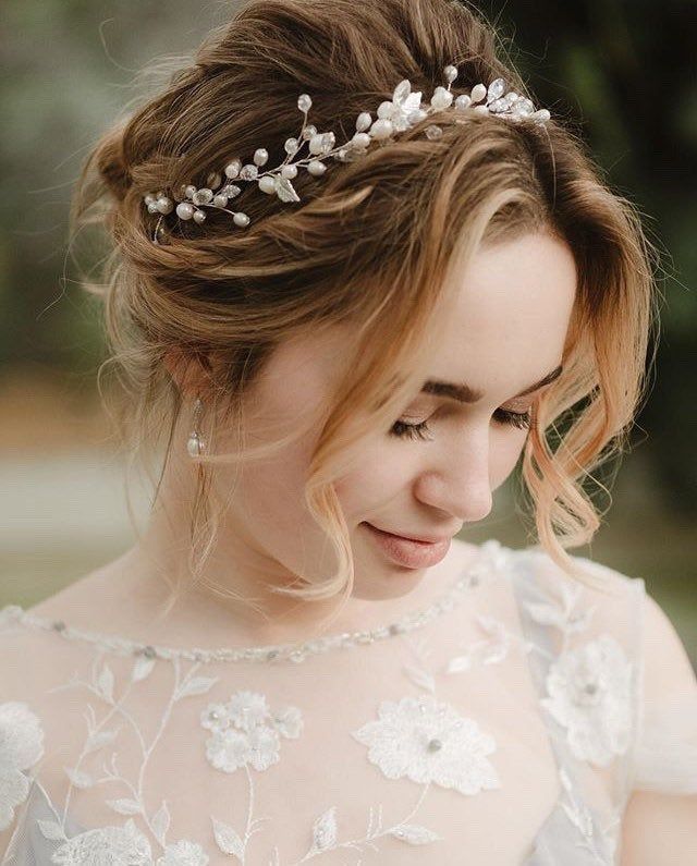 a woman wearing a tiara with flowers on her head looking down at the ground