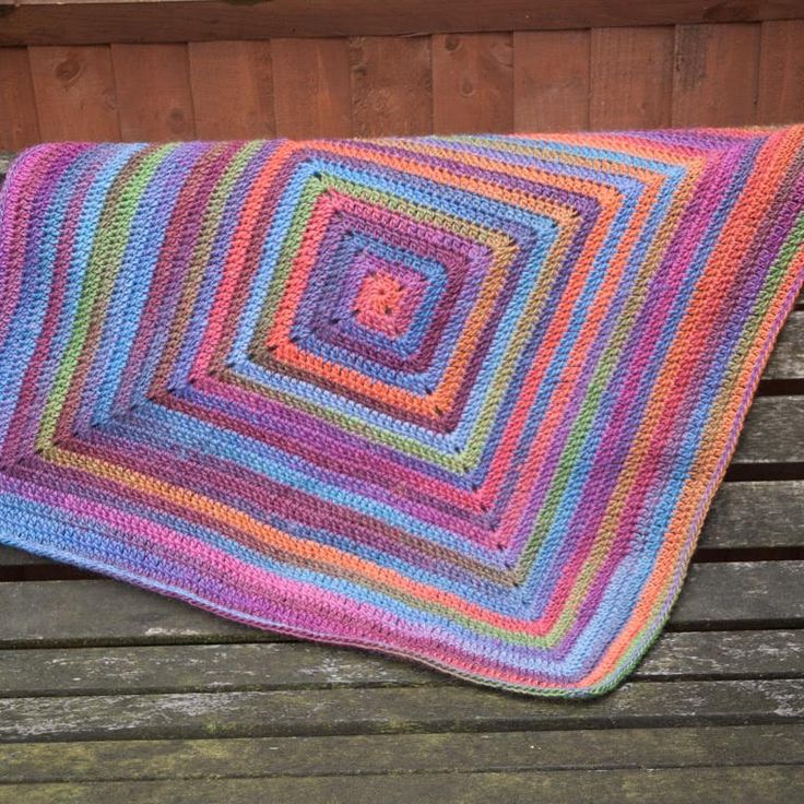 a crocheted blanket sitting on top of a wooden bench