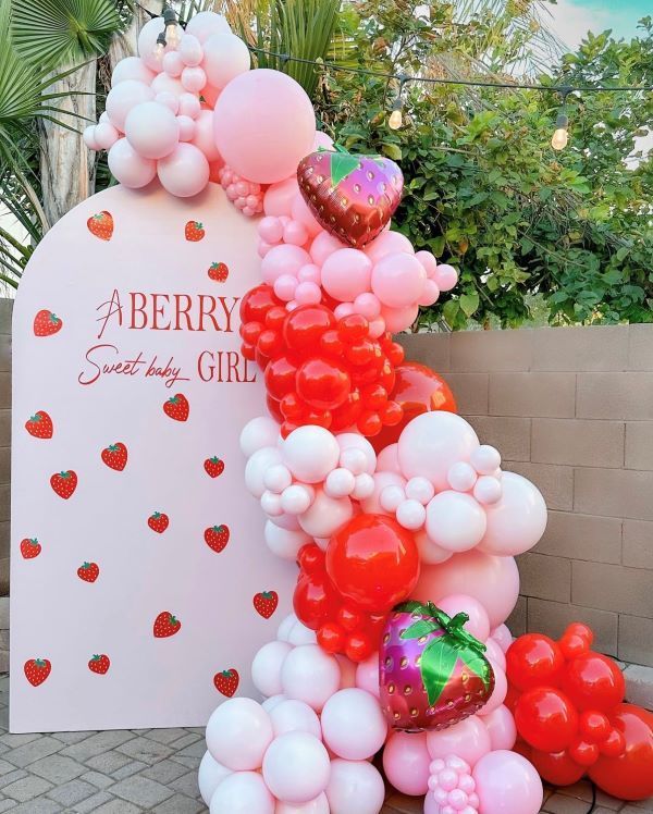 a bunch of balloons that are in the shape of a strawberry on top of a sign