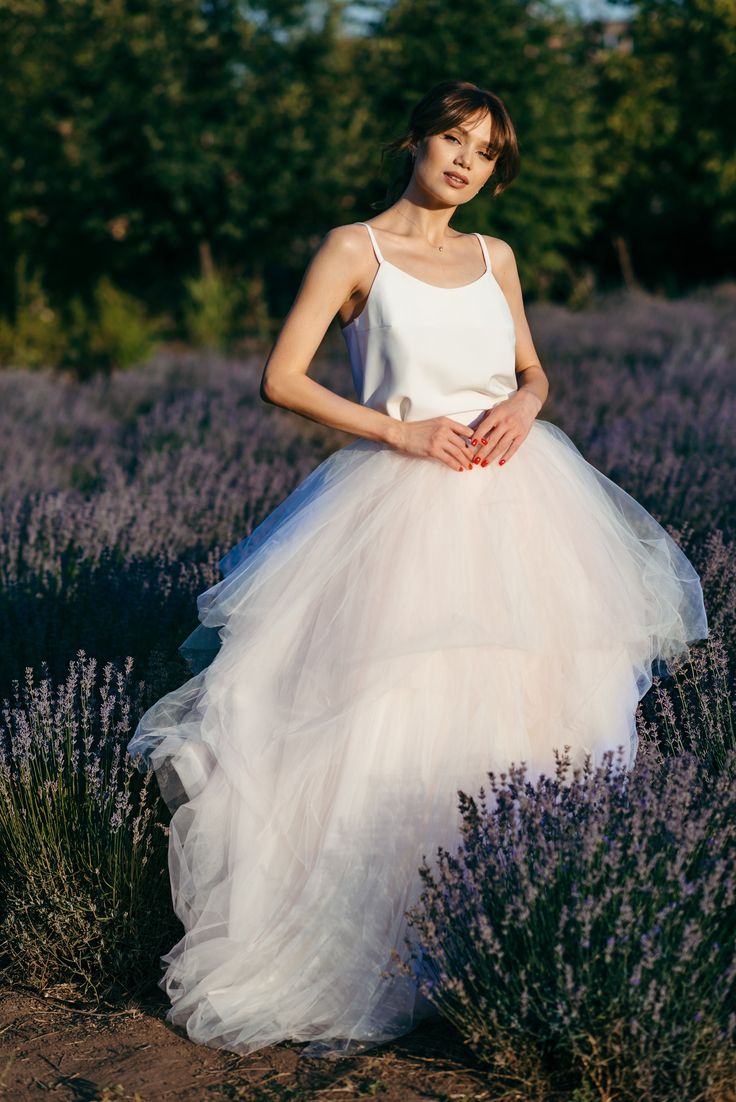 a woman in a white dress standing in a lavender field with her hands on her hips