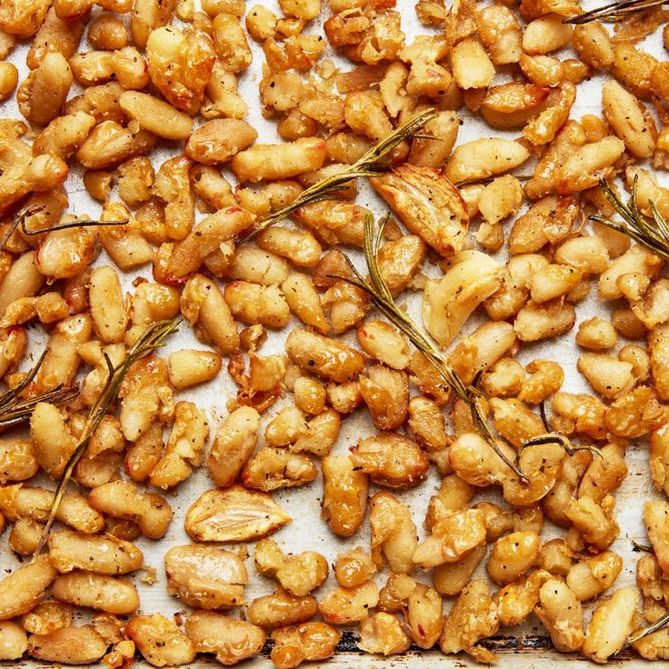 nuts are arranged on a baking sheet with some sprigs in the middle and seasoning