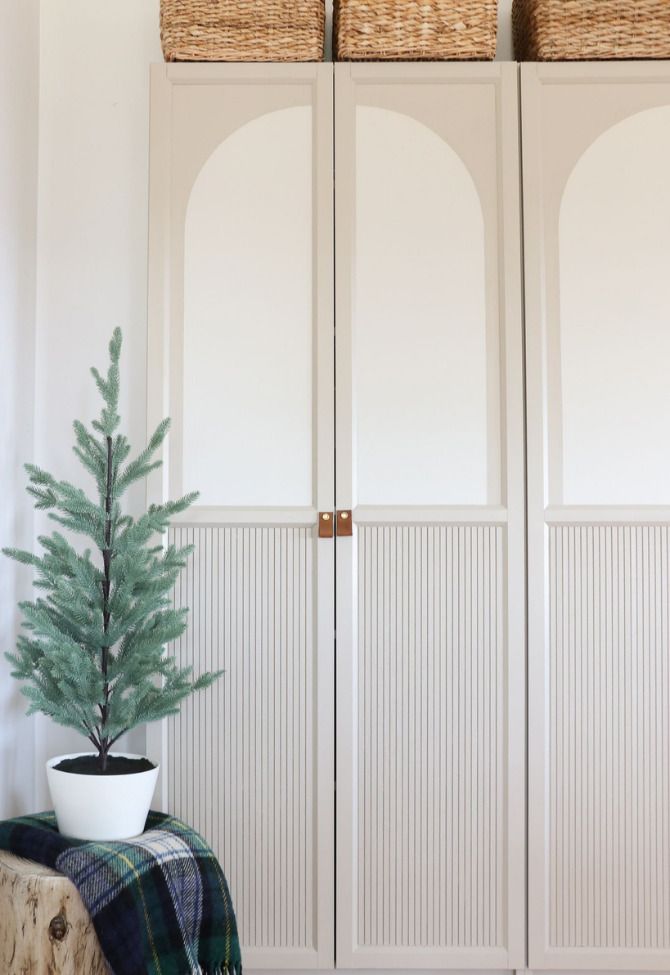 a small christmas tree in a white pot on a bench next to two large closet doors