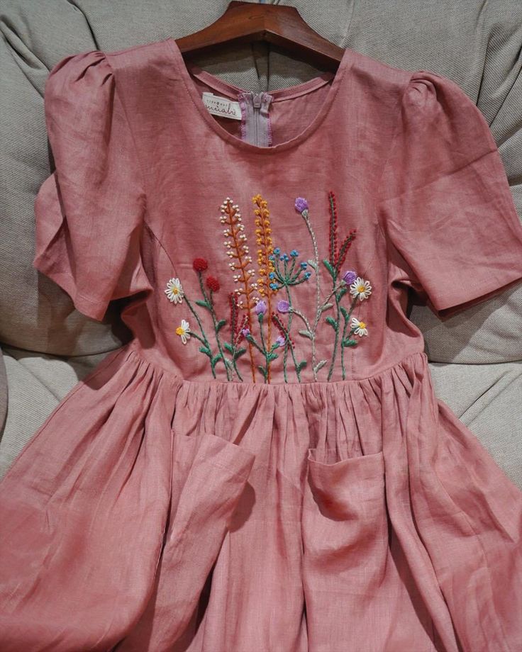 a pink dress with flowers on it sitting on a couch