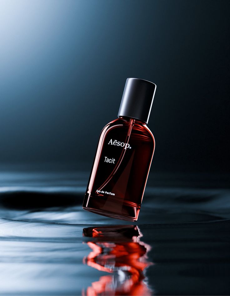 an empty bottle of perfume sitting on top of a reflective surface in front of a blue background