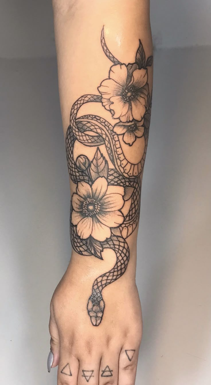 a woman's foot with a snake and flowers tattoo on it