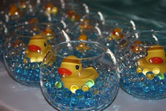 several clear bowls filled with blue beads and yellow rubber ducks