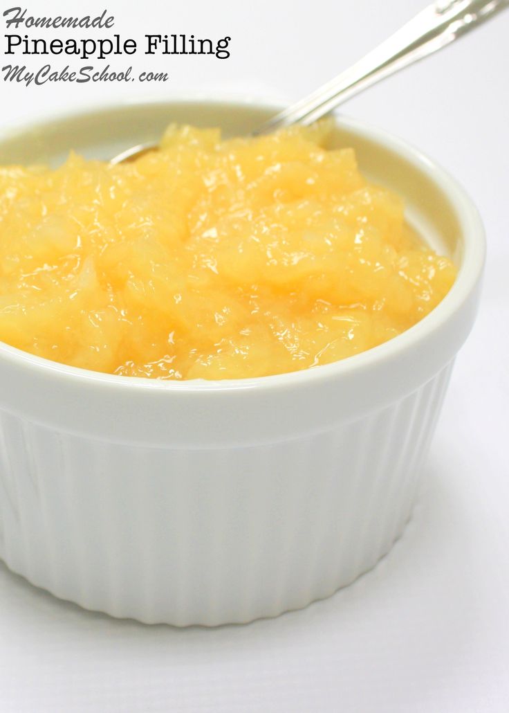 a bowl filled with pineapple filling on top of a white table next to a spoon