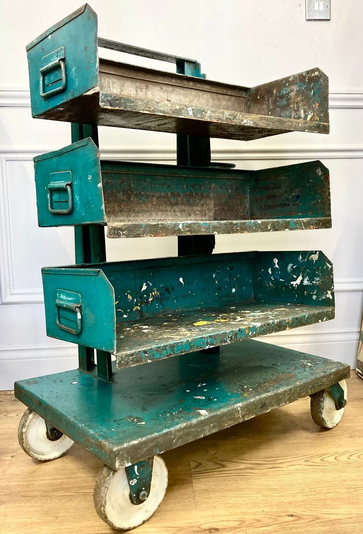 an old green metal cart with drawers on wheels