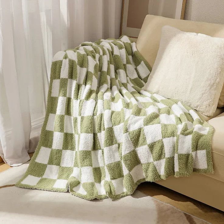 a green and white checkered blanket sitting on top of a couch next to pillows