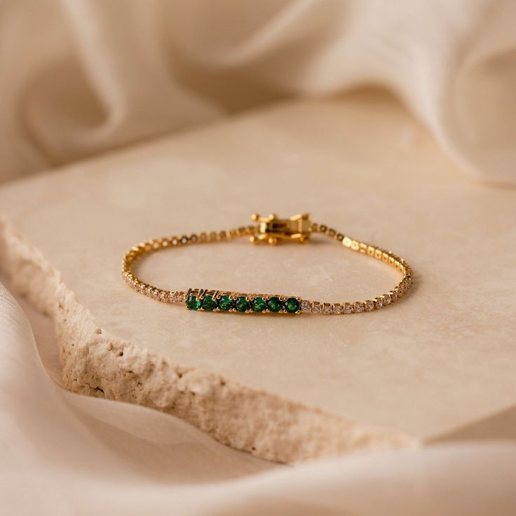 Have a friend’s birthday coming up? Our Emerald Tennis Bracelet is the one for you! The rich Emerald gemstone is said to bring wisdom and growth, perfect for a new year of life. Diamond stones surround the remaining chain of the bracelet, leaving no space on this jewelry piece untouched with glamour. Giving this bracelet will make their birthday one they’ll never forget. Finish/Material: 18K Gold Over Brass Featuring ~1.5mm CZ Diamonds and ~3mm CZ Emerald Gemstones Part of our Diamond and Pavé C Yellow Gold May Birthstone Bracelets For Anniversary, Yellow Gold Bracelets For Anniversary, May Birthstone, Fine Jewelry Tennis Bracelet Bangle Gift, Fine Jewelry Tennis Bracelet Gift, Gold Bracelets For Anniversary With May Birthstone, Yellow Gold Jubilee Bracelet With May Birthstone, Yellow Gold Jubilee Bracelet, May Birthstone, Yellow Gold Jubilee Bracelet For May Birthstone, Diamond Bracelet With Box Chain As Gift