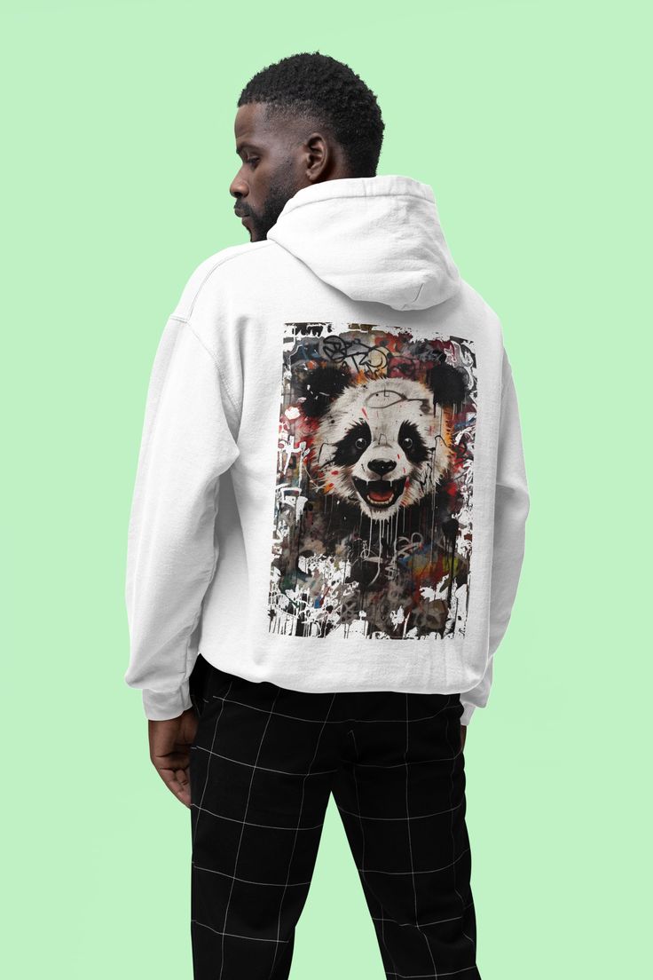 Immerse yourself in the exciting world of street art with our "Urban Panda" graffiti-style shirt. This unique design combines the majestic calm of a panda with the rebellious energy of the street. Product features:
 * Material: 80% cotton, 20% polyester * Grammage: 280 g/m² * Cut: regular fit * Double seam processing * Roughened inside * Hood cord in identical color * Double layer hood * Kangaroo pocket on the front * Knitted cuffs on sleeves and hem Urban Crew Neck Hoodie With Graffiti Print, White Cotton Hoodie With Graffiti Print, Urban Hoodie With Graphic Print, Urban Cotton Hoodie With Graffiti Print, Urban Graffiti Print Sweatshirt For Streetwear, Urban Sweatshirt With Graffiti Print For Streetwear, Artistic Graphic Print Sweatshirt For Streetwear, Urban Cotton Sweatshirt With Graffiti Print, Artistic Cotton Sweatshirt For Streetwear