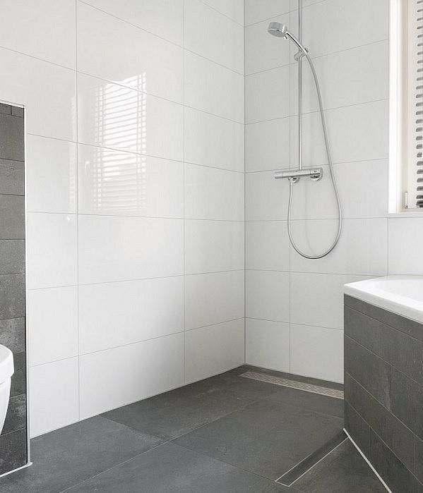 a white bathroom with grey tile flooring and walls