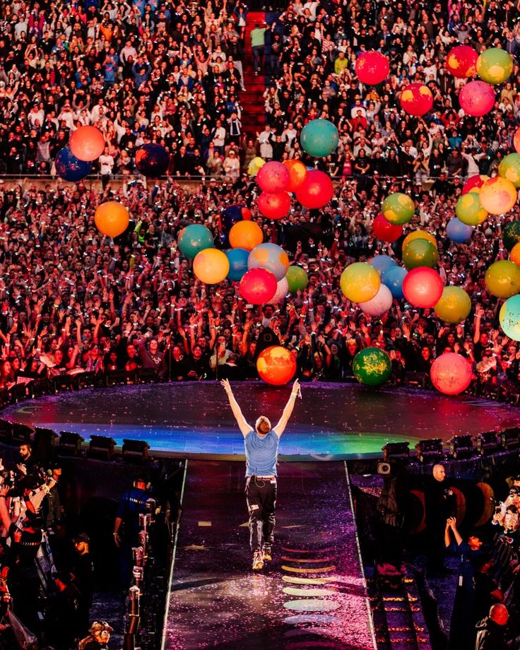 a man standing on top of a stage with lots of balloons in front of him