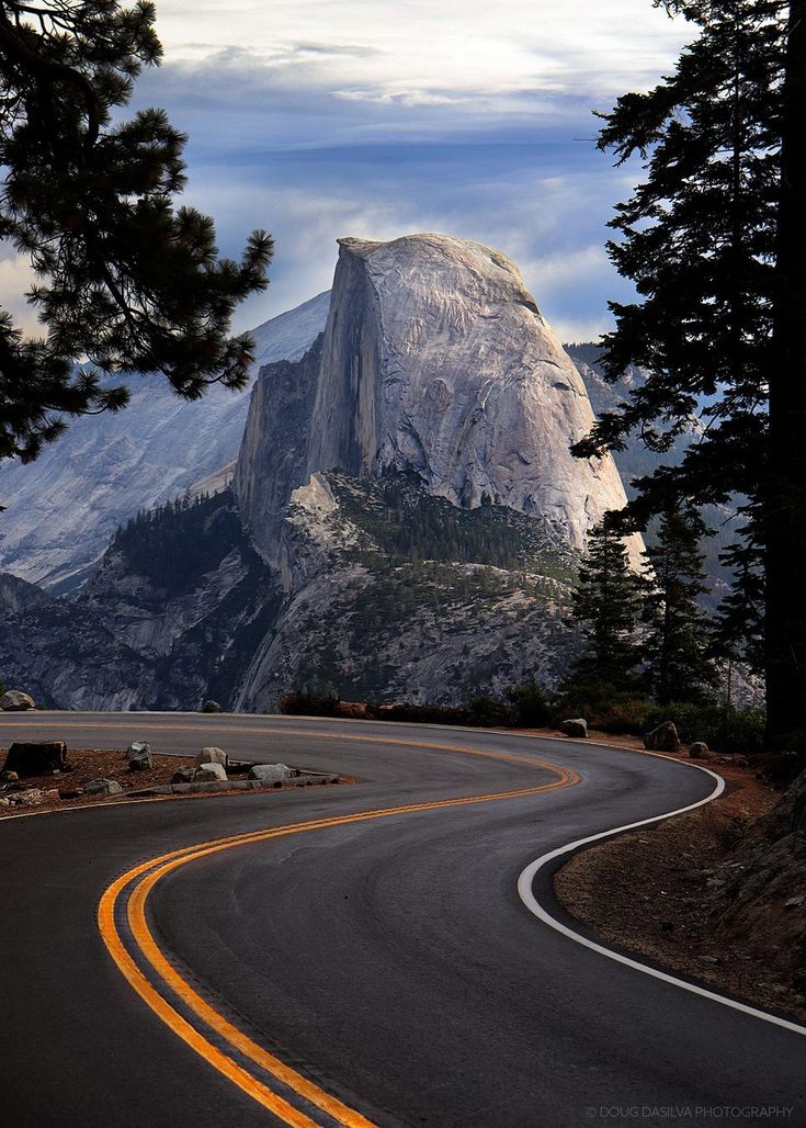 a curved road with a mountain in the background