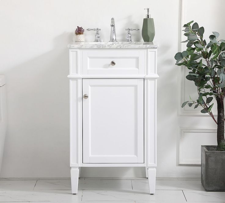 a white bathroom vanity with two sinks and a potted plant in front of it