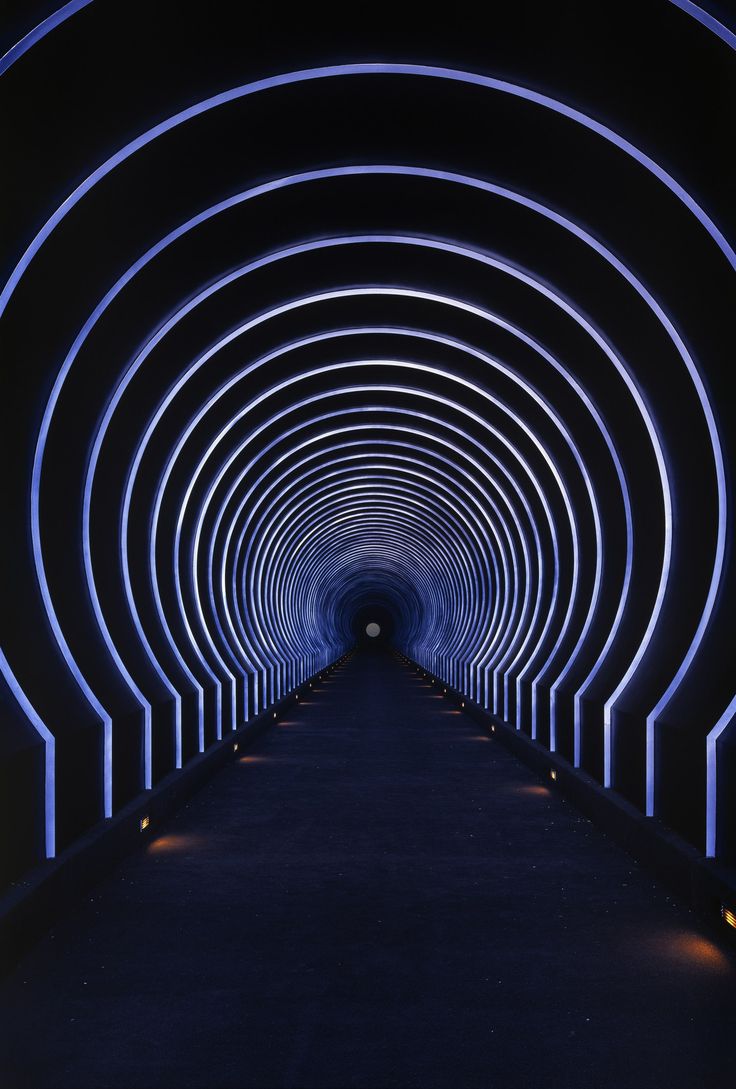 a long tunnel with blue lights in the middle and black walls on both sides that lead into another tunnel