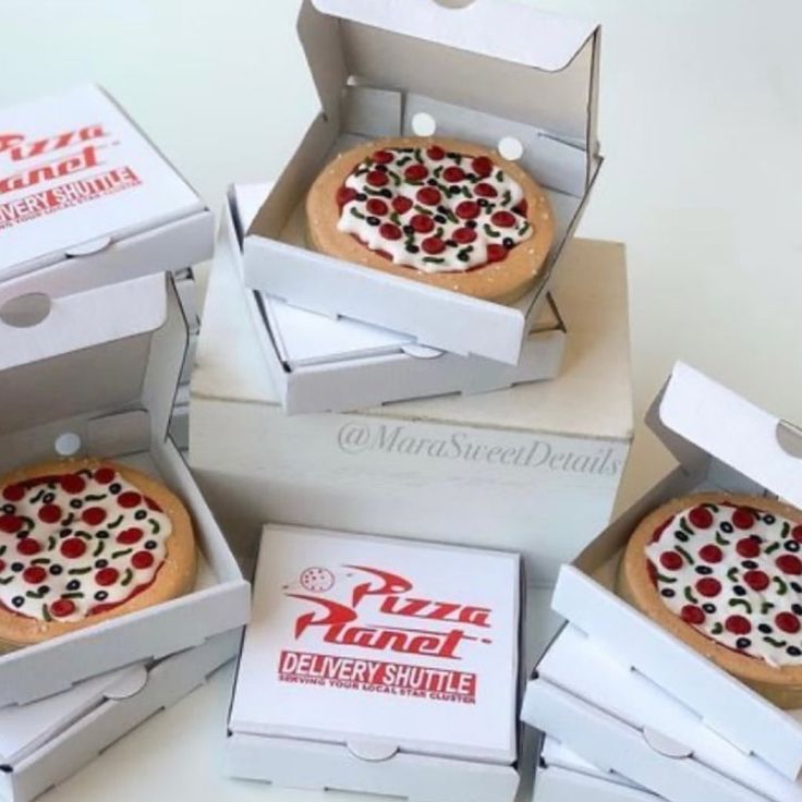 four pizza boxes with different types of pizza in them on top of a white table