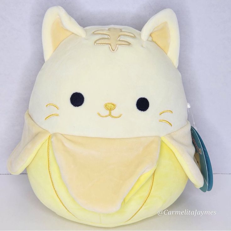 a white cat stuffed animal with a yellow blanket around it's neck and eyes