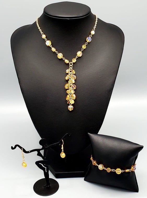 This mesmerizing golden crystal beaded custom mini set comes with a necklace and complimentary earrings and a clasp bracelet.Necklace - "Cosmic Charisma": Dipped in a rainbow iridescence, a faceted collection of golden crystal-like beads delicately links below the collar. A tassel of matching beads cascades from the center, creating a stellar extended pendant. Features an adjustable clasp closure. Includes one pair of matching earrings. Bracelet - "Colorfully Cosmic": Dipped in a rainbow iridesc Adjustable Beaded Citrine Jewelry, Yellow Citrine Jewelry With Faceted Beads, Adjustable Iridescent Dangle Jewelry, Faceted Yellow Citrine Jewelry, Yellow Faceted Citrine Jewelry, Iridescent Crystal Dangle Jewelry, Gold Beaded Jewelry With Czech Glass, Faceted Citrine Beads Jewelry, Citrine Faceted Round Beads Jewelry