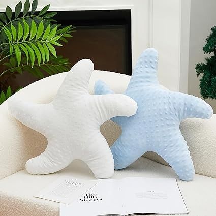 two starfish pillows sitting on top of a white couch next to a green plant