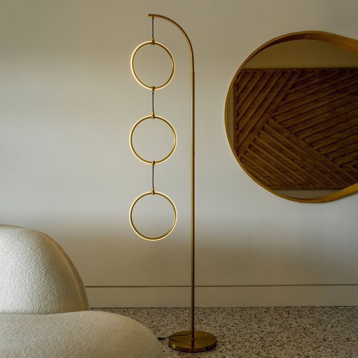 a floor lamp that is next to a round mirror on the wall in a room