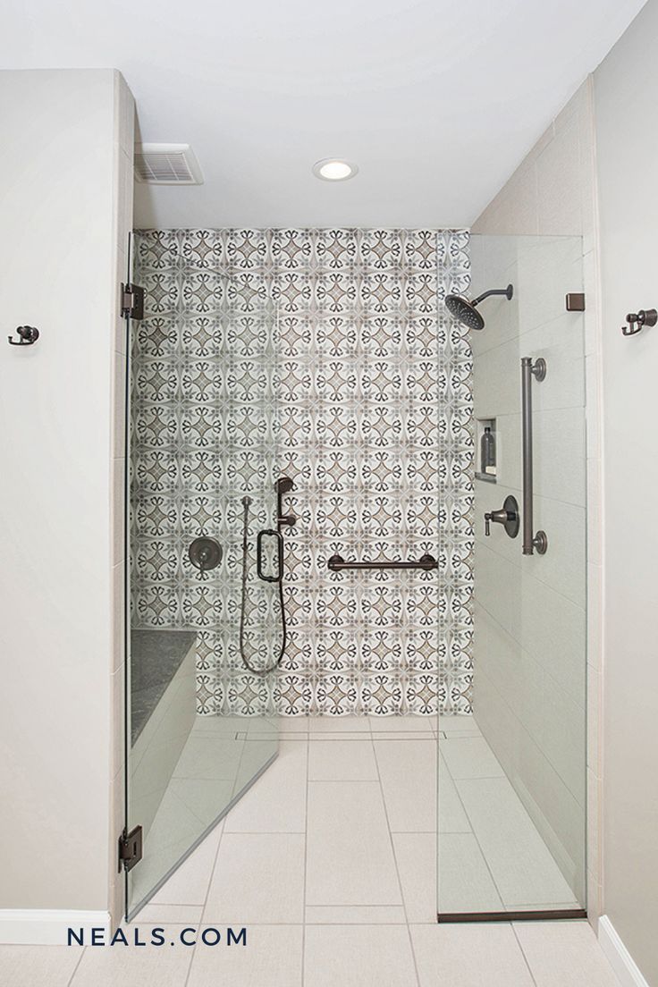 a walk in shower sitting next to a white tiled wall and floor covered in black and white tiles