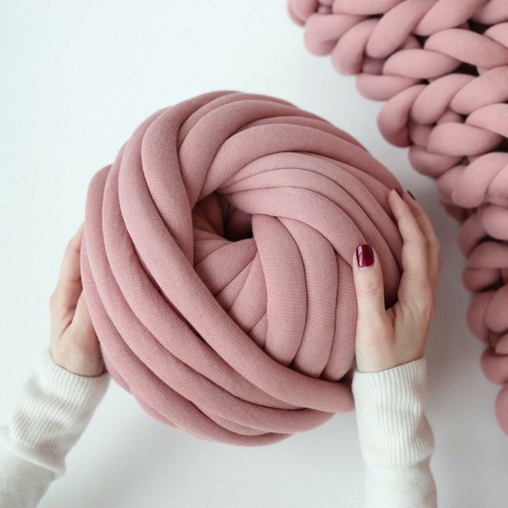 a woman is holding up a large pink object that looks like a ball of yarn