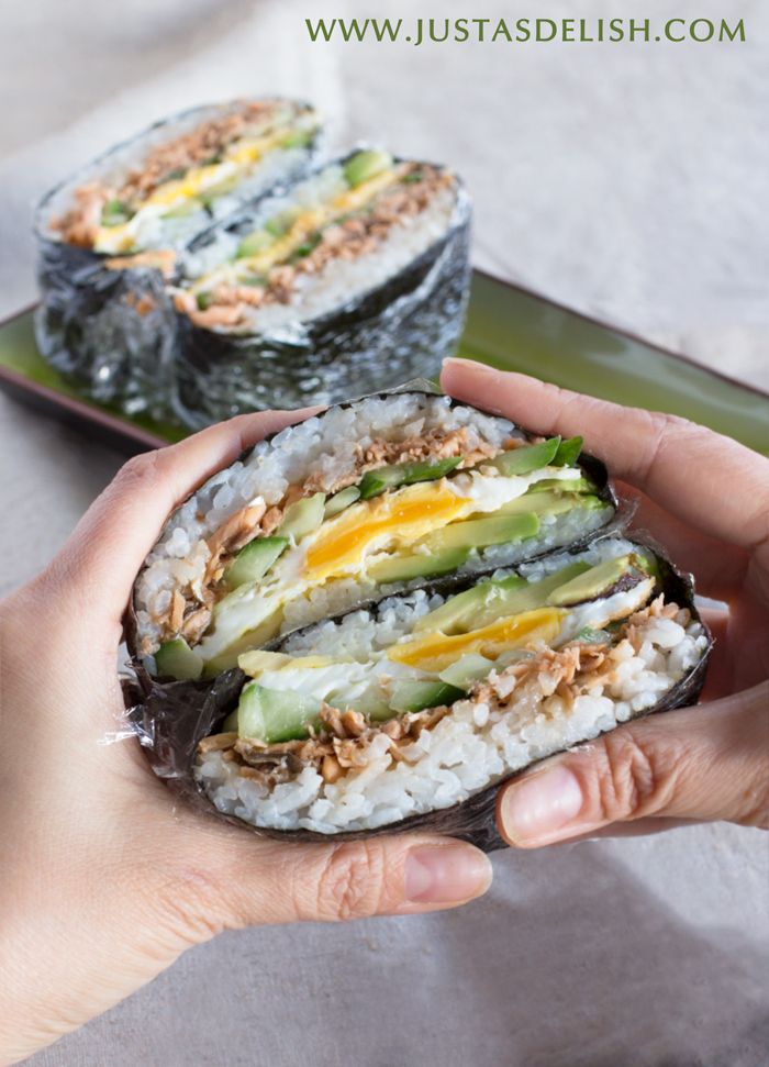 someone is holding up a sushi with cucumber and avocado on it