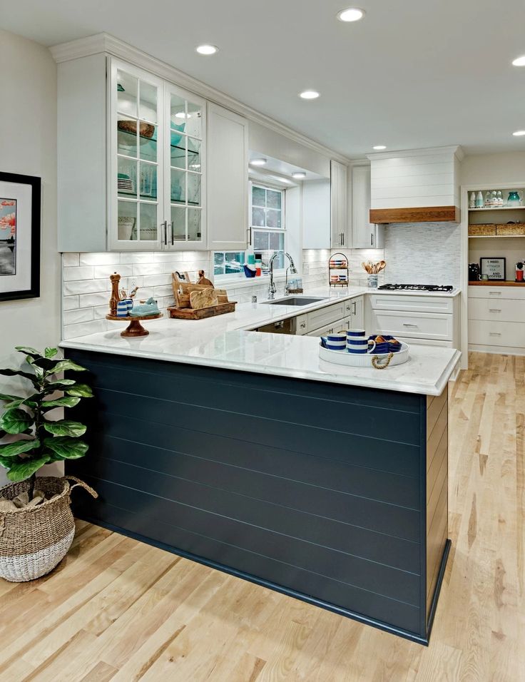 a large kitchen with white cabinets and wood flooring, along with an island in the middle