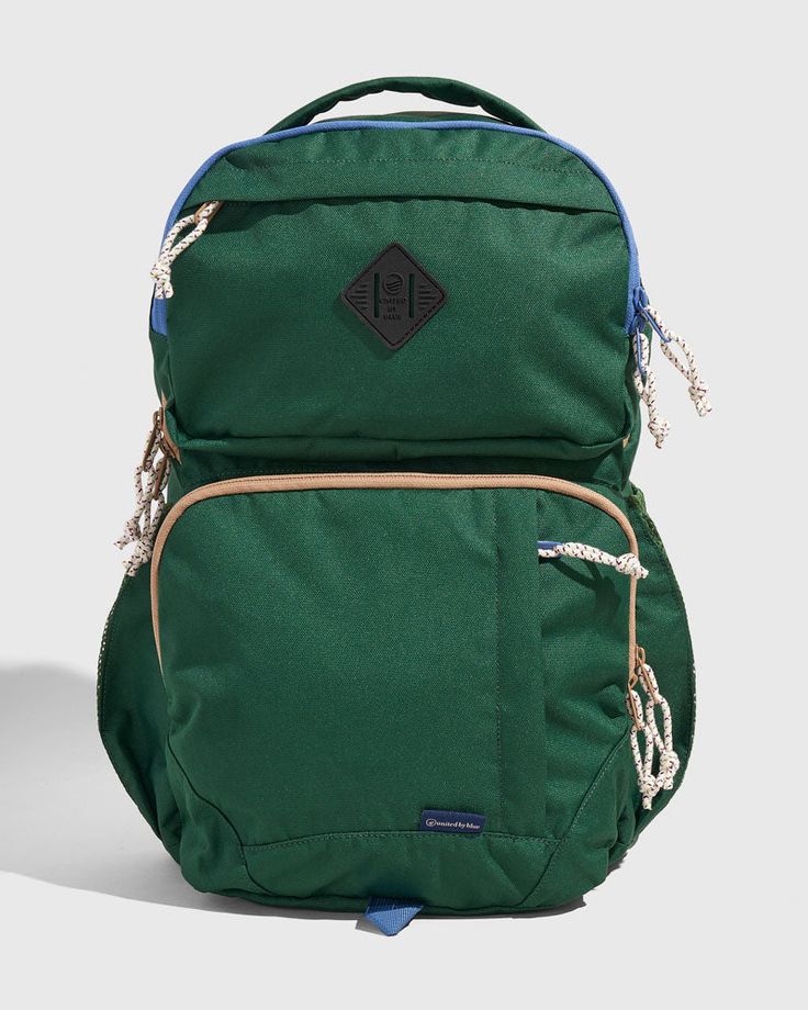 a green and blue backpack sitting on top of a white floor