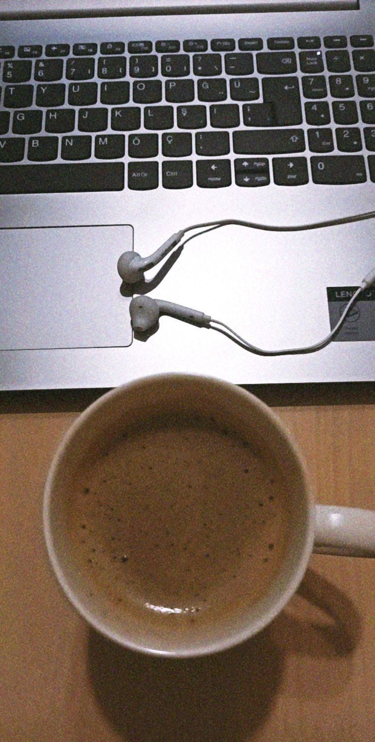 a cup of coffee sitting in front of a laptop computer