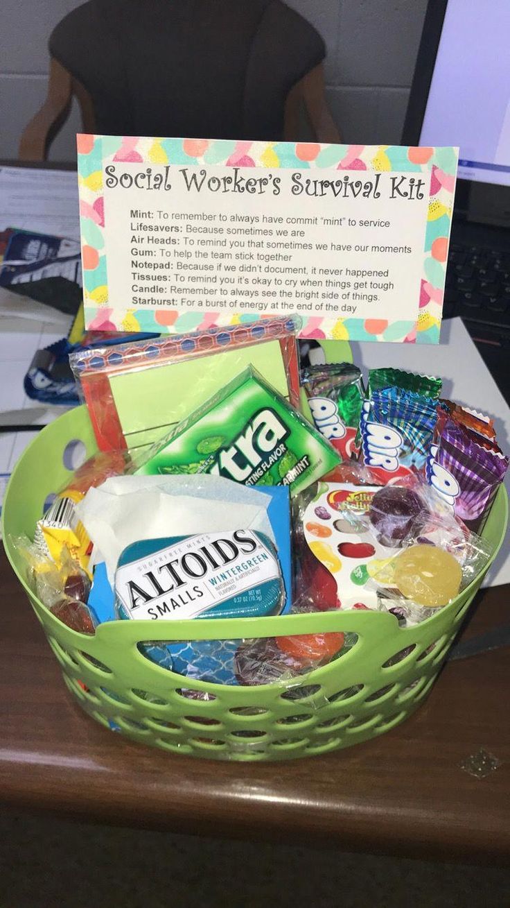 a green basket filled with lots of items on top of a wooden desk next to a computer