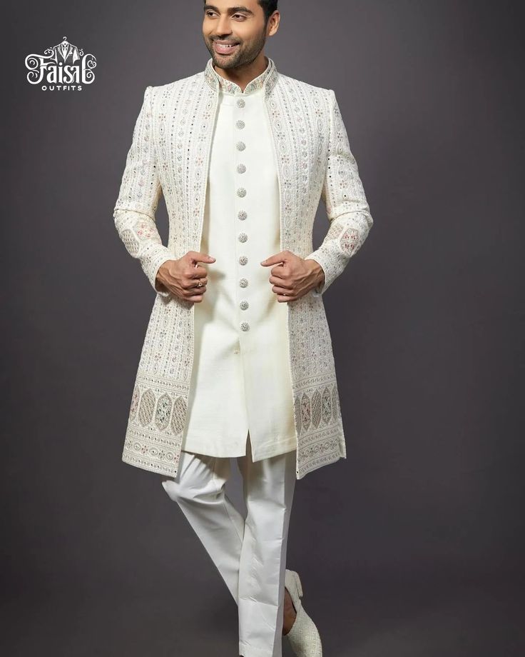 a man in a white sherwa with his hands on his hips, standing and smiling