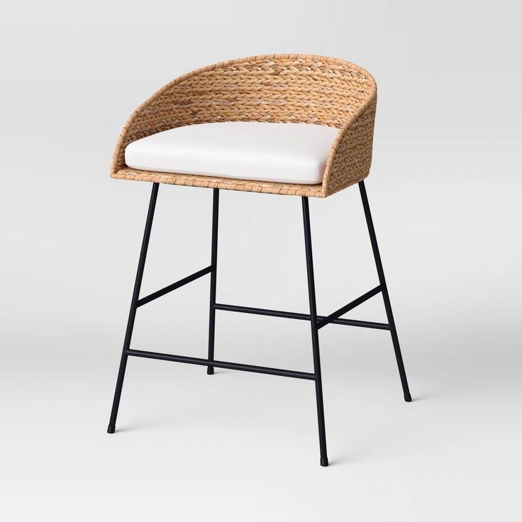 a wicker stool with a white cushion and black metal frame on an isolated background