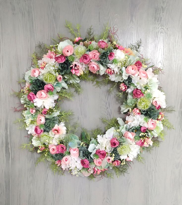 a wreath with pink and white flowers hanging on a wall