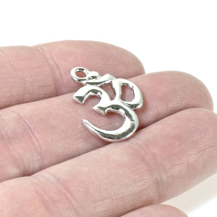 Material: Pewter, Plated with Rhodium Amount: 1 pendant Size: Approximately 17mm x 22mm Shape: Aum/Ohm/Om symbol Color: Bright silver A sacred Hindu symbol representing the essence of the universe. Wear it to remind yourself to slow down and breathe in life. Silver Personalized Spiritual Charms, Personalized Spiritual Silver Charms, Nickel-free Spiritual Jewelry And Charms For Jewelry Making, Silver Round Pendant Spiritual Charm, Spiritual Silver Charm Necklace Nickel Free, Nickel Free Symbolic Silver Charm Necklaces, Silver Symbolic Nickel-free Charm Necklaces, Nickel-free Symbolic Silver Charm Necklace, Nickel-free Silver Charm Necklaces For Meditation