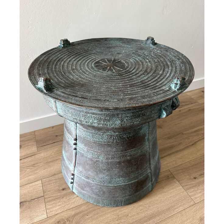 an old round metal container sitting on top of a wooden floor