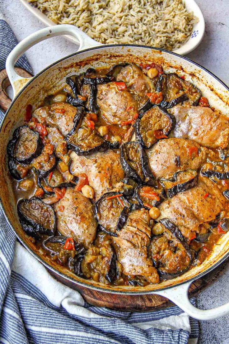 a pan filled with meat and vegetables sitting on top of a table next to rice