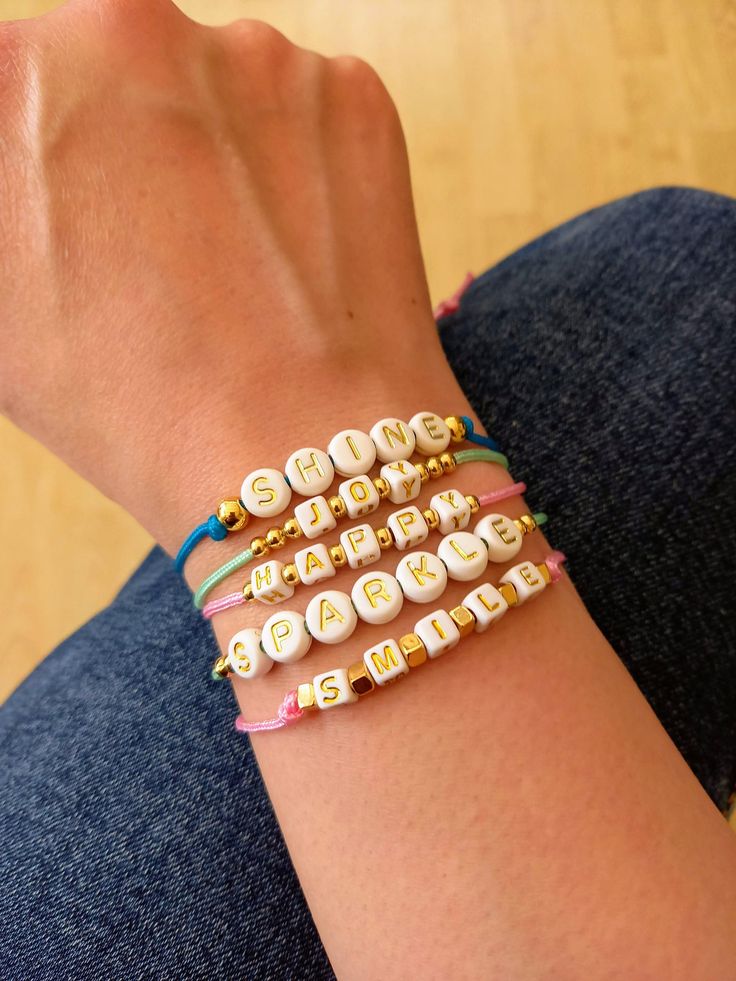 Beaded custom word bracelet. Send some positivity with these cute sentiment bracelets. Five different uplifting words to choose from- Sparkle, Shine, Joy, Happy and Smile. If you would like a different word then please message me! Comprised of- Smile- pink macramé cord (1.5mm)            Acrylic letter cube beads (5mm)            Gold plated cube beads (3mm) Sparkle- Light green macramé cord (1.5mm)               Acrylic letter coin beads (7mm)               Gold plated beads (3mm) Joy- Light green macramé bead cord (1.5mm)         Acrylic letter cube beads (5mm)         Gold plated beads (3mm) Happy- Pink macramé beads cord (1.5mm)              Acrylic letter cube beads (5mm)              Gold plated beads (3mm) Shine- Blue macramé bead cord (1,5mm)            Acrylic letter coin beads (7 Presentation Cards, Glassine Bags, Word Bracelet, Cube Beads, Acrylic Letters, Uplifting Words, Bracelet Friendship, Writing Gifts, Macrame Cord