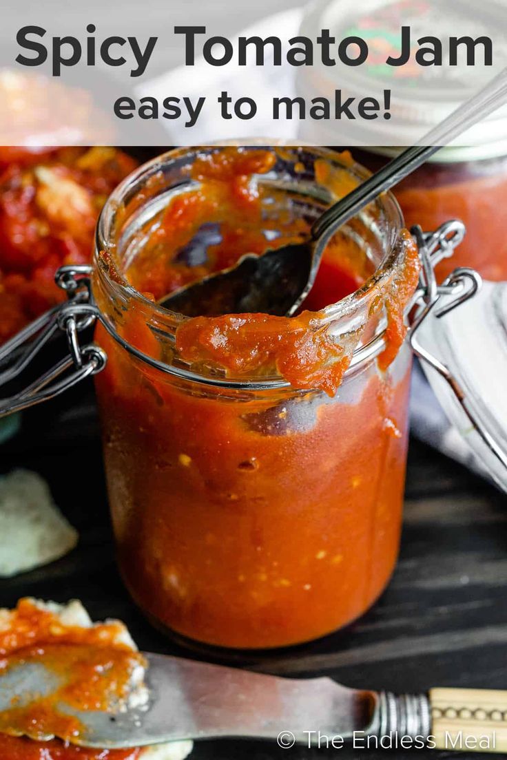 a jar filled with tomato sauce next to a fork and spoon on top of a table